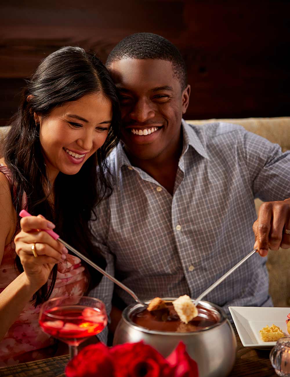 a man and woman smiling while eating fondue